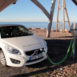 Electric Volvo charging at Giraffe 2.0 wind turbine solar PV charger on wooden construction by InnoVentum